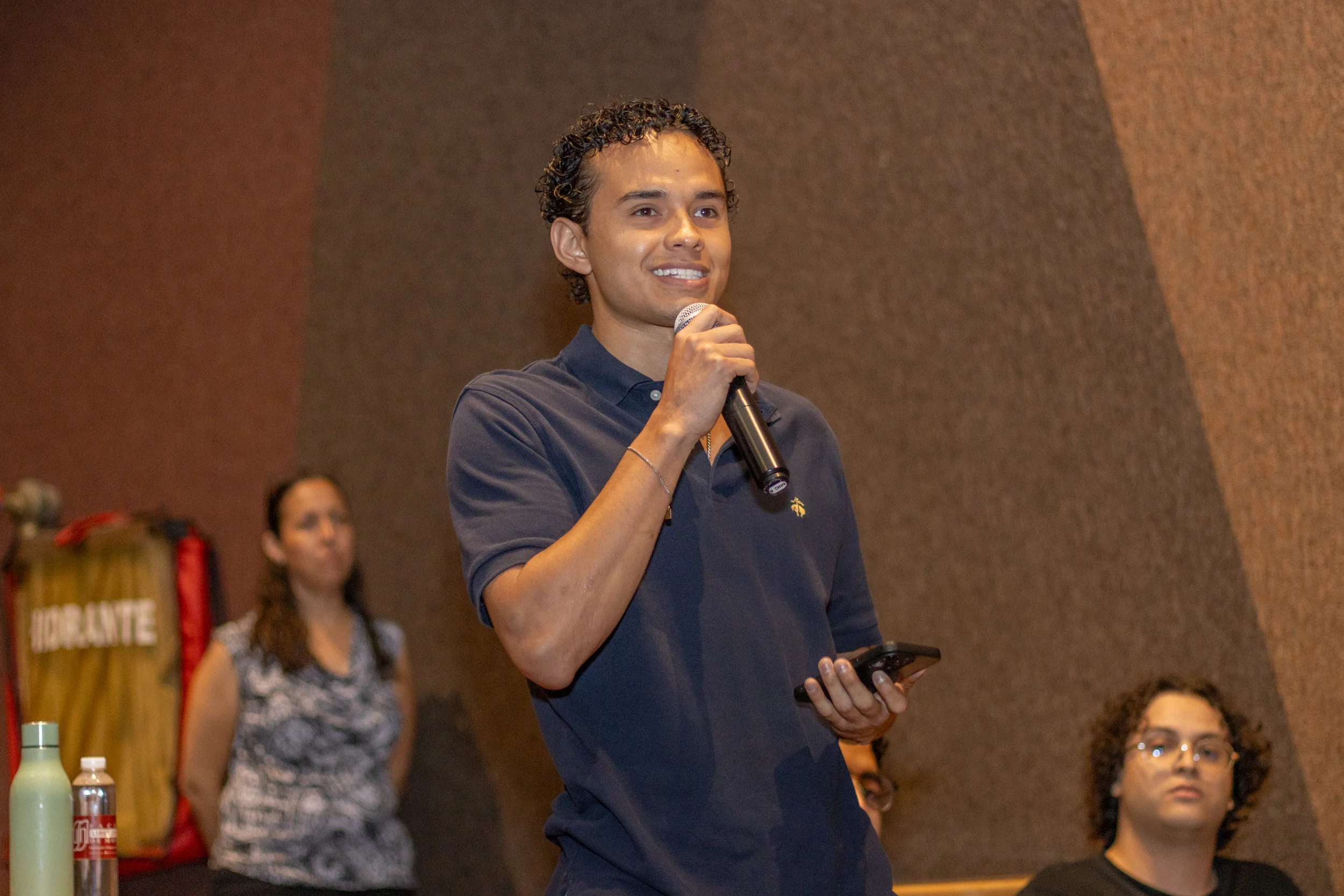 Estudiante de la FLDM sonrie mientras habla con microfono en un evento
