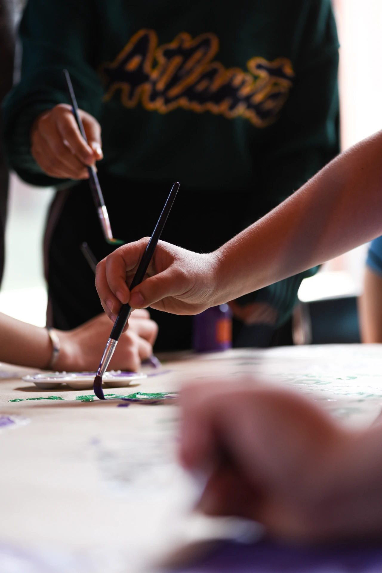 Manos de estudiantes pintando en un taller de arte y cultura